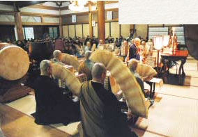 New Year prayers. Priests manipulate accordion-pleated sutras in flowing arcs.